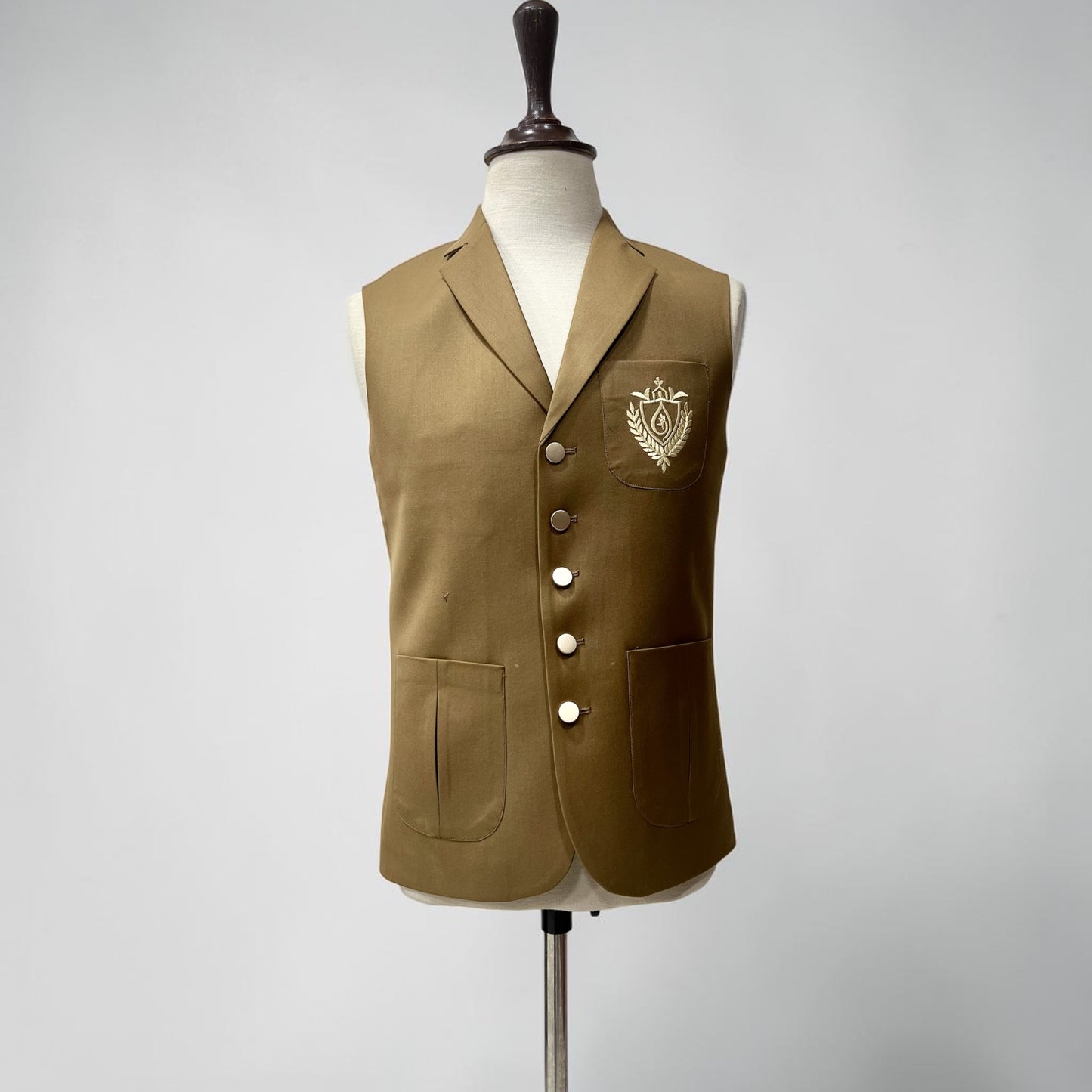 Brown vest with a crest on a mannequin against a gray background