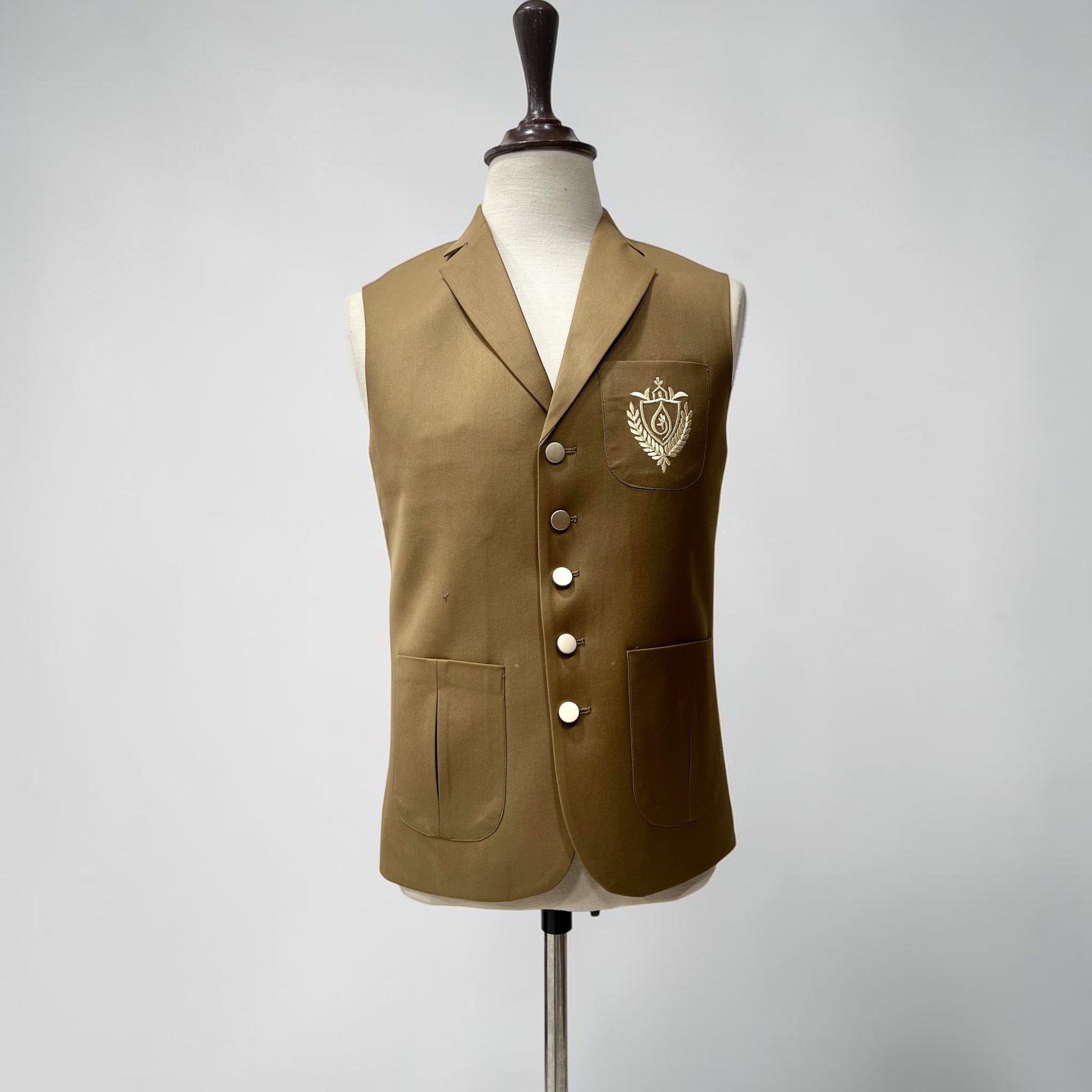 Brown vest with a crest on a mannequin against a gray background
