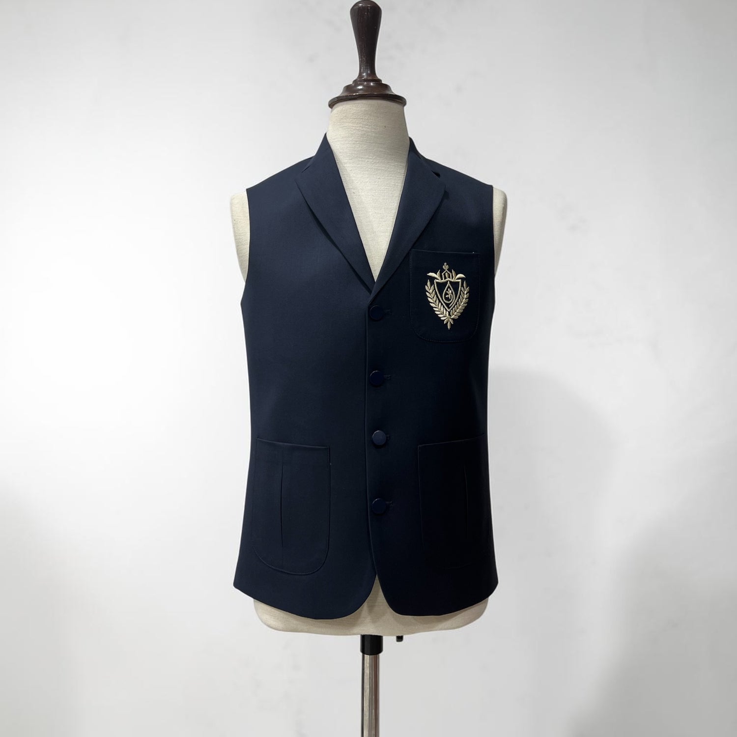 Navy blue blazer with a crest on a mannequin against a white background