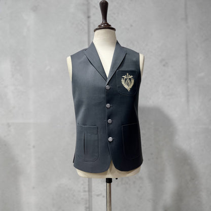 Dark gray vest with a crest on a mannequin against a gray background